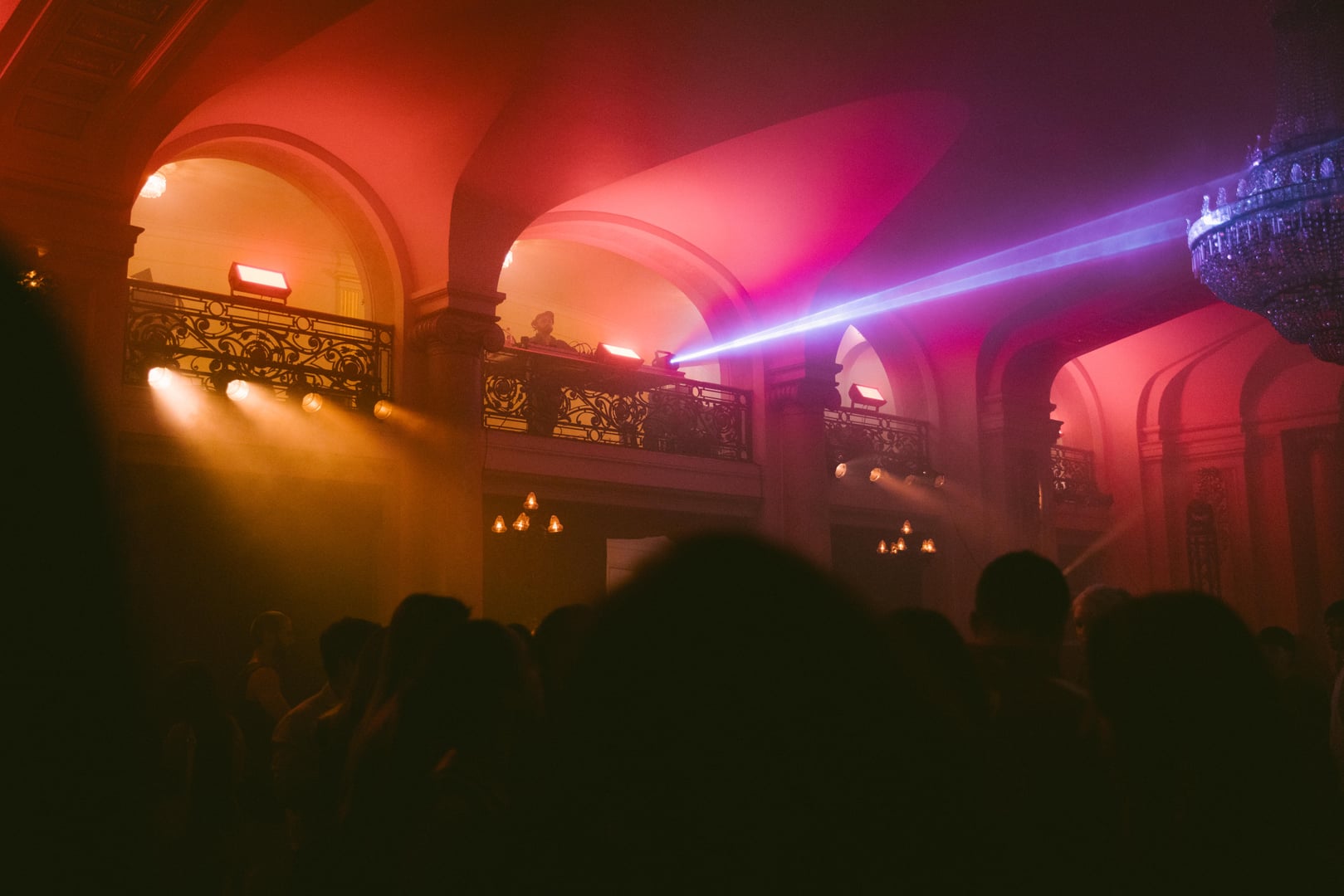 Público en el foyer con luces rojas y rayo láser